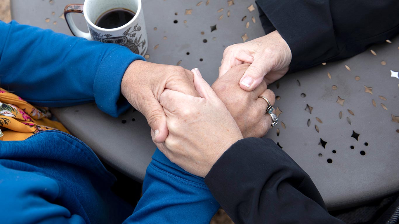 2 women holding hands over table close up