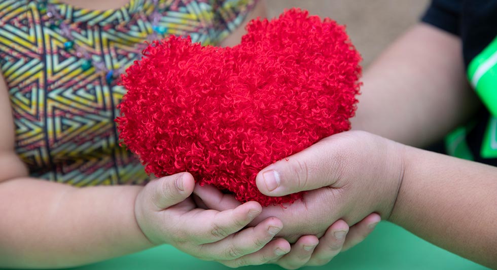 kids hands holding toy fuzzy heart