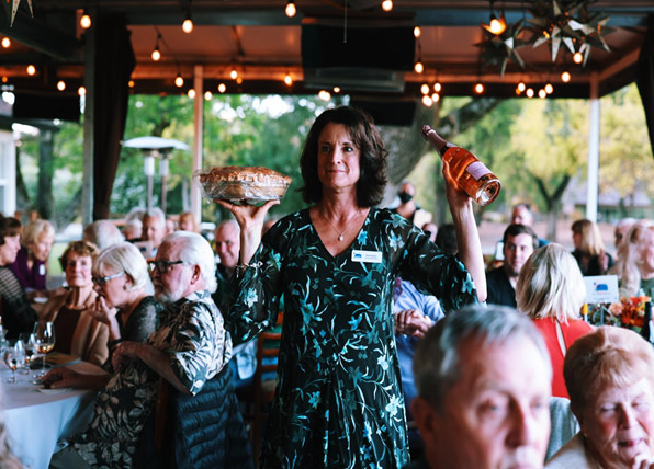 woman at restaurant holding pie and wine